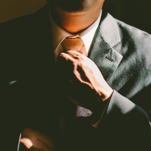 Man in gray suit straightening his necktie