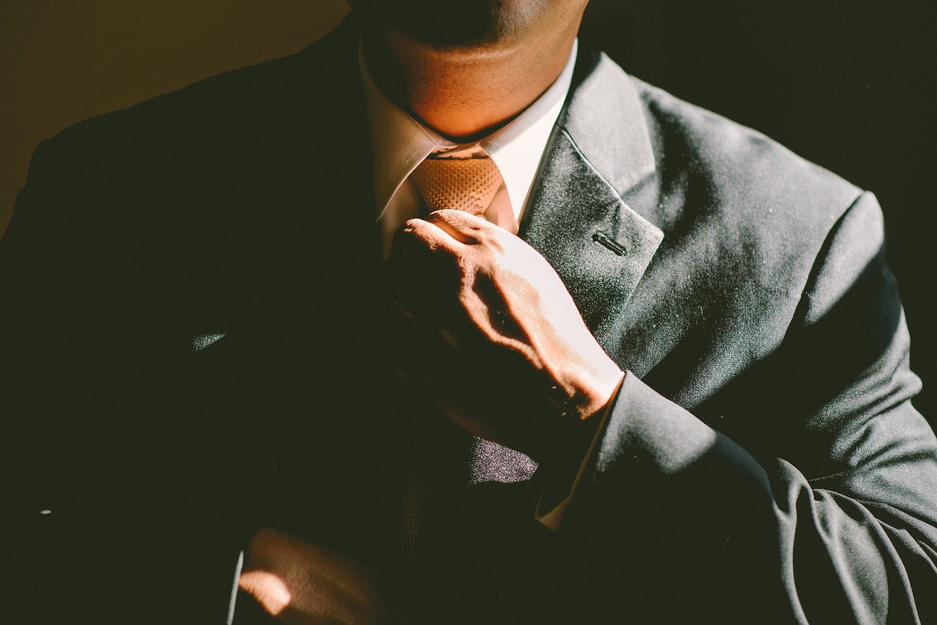 Man in gray suit straightening his necktie