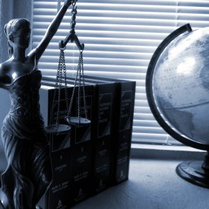Lady justice, books, and a globe on a desk