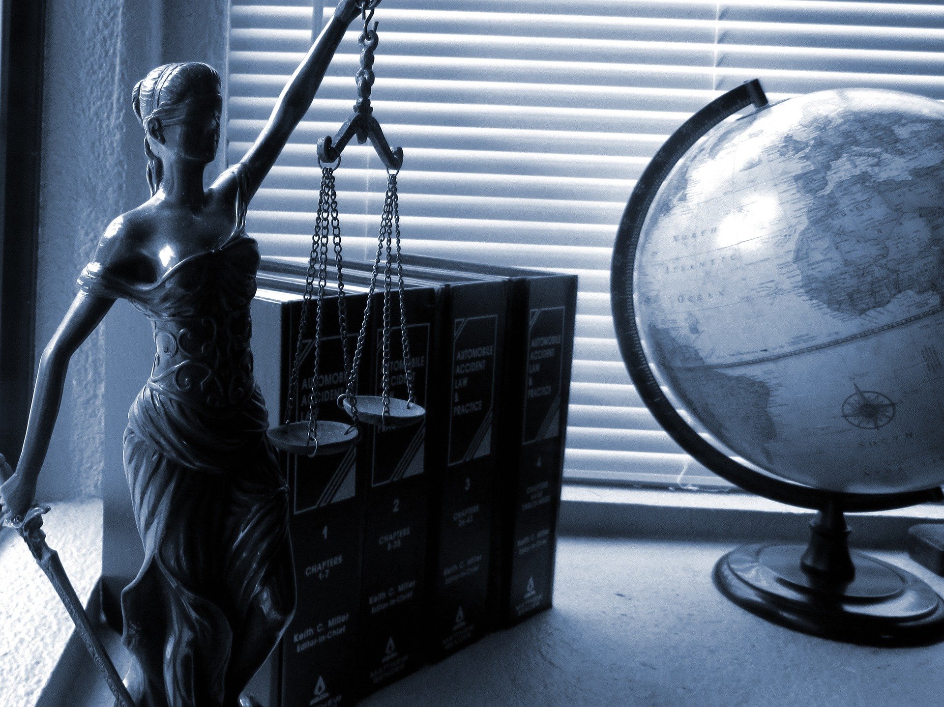 Lady justice, books, and a globe on a desk