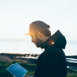 A young man looking at a tablet outside